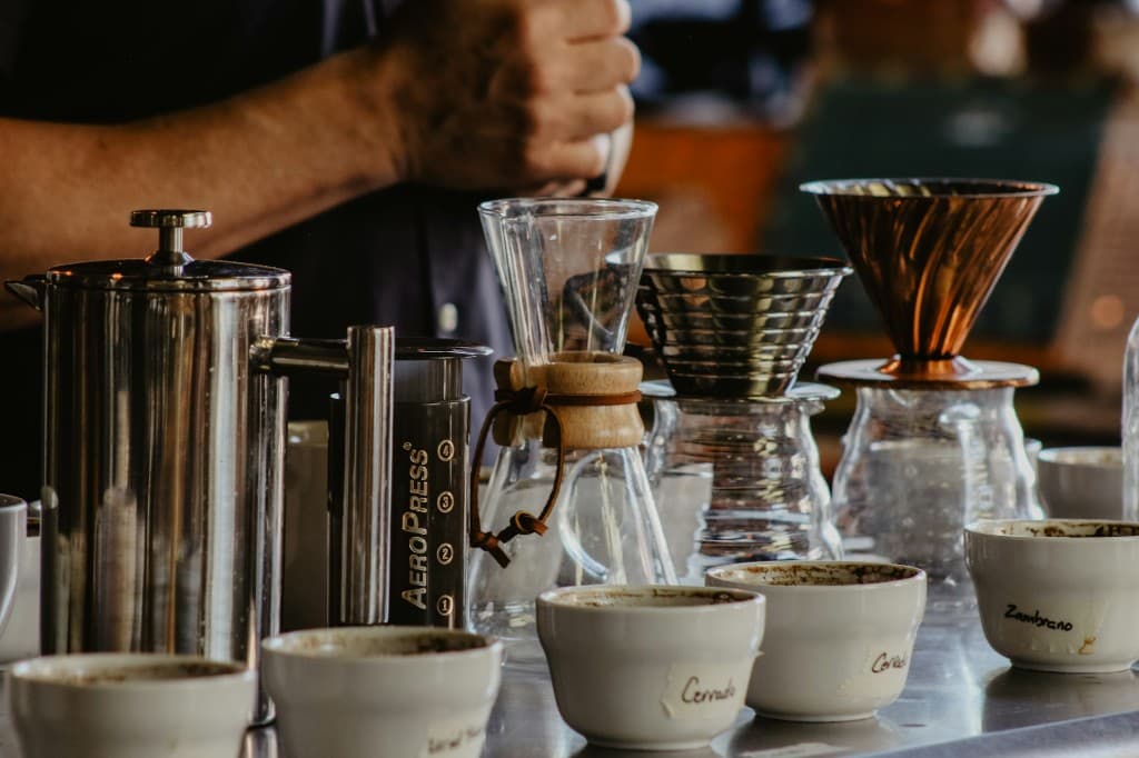 French press, AeroPress, Chemex, and pour-over drippers lined up on a counter with cupping bowls